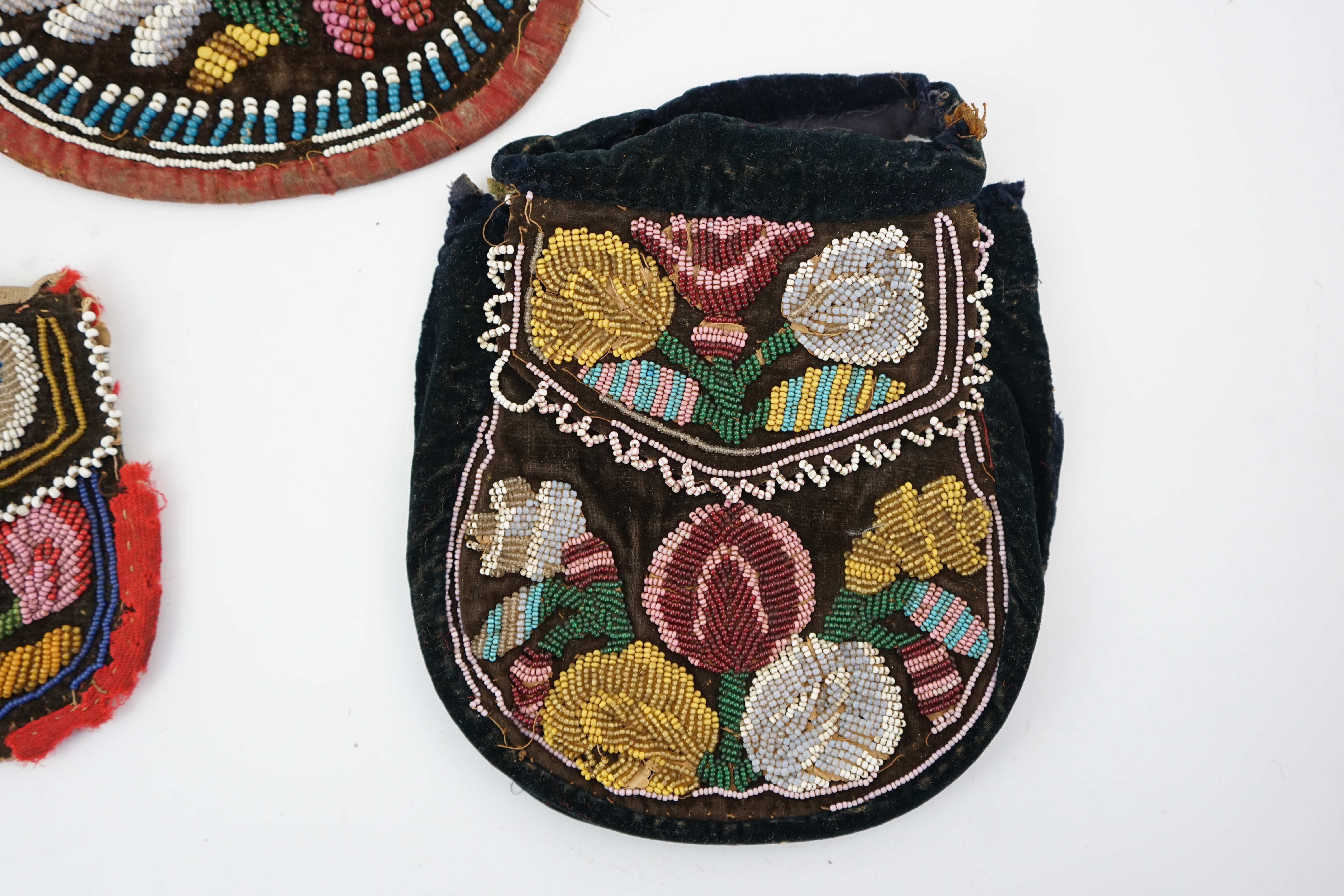 Four 19th century Iroquois Native American beaded bags, three large and one smaller, all bags worked in various colours and differing designs, all with flaps and same pattern both sides, largest 19cm high. Condition - al